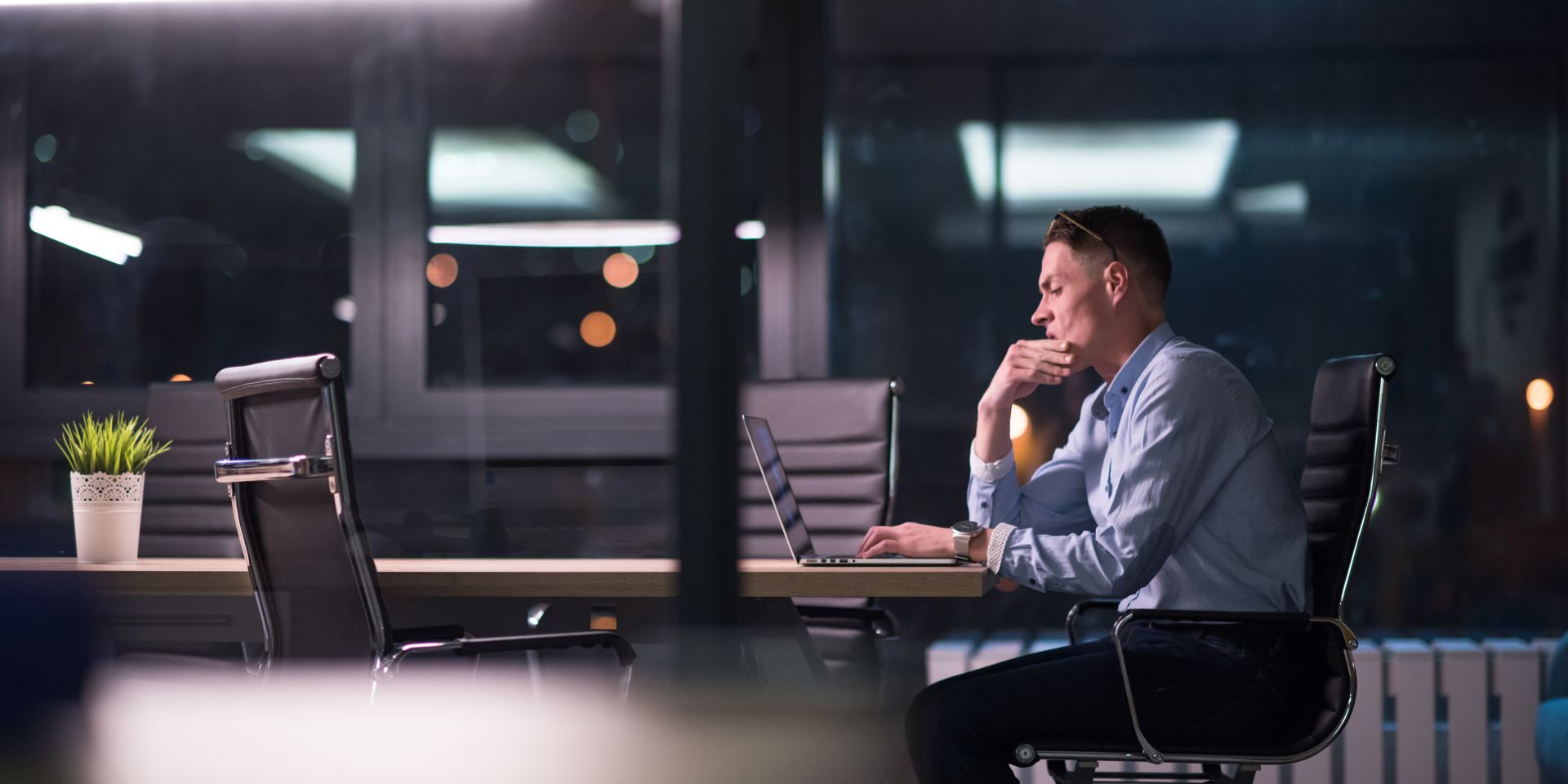 Young man working on laptop at night in dark office. The designer works in the later time.